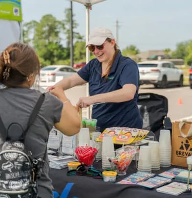 woman standing behind table passes out information at booth