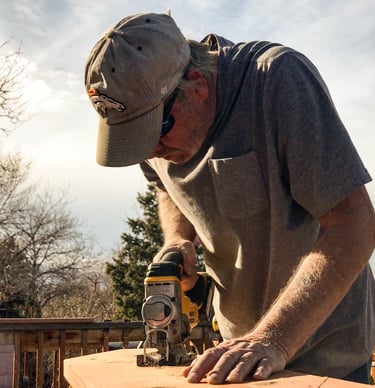 Brewer Construction carpenter using an impact driver on a wooden deck structure in Evergreen.