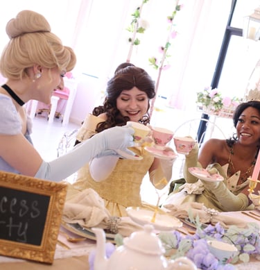 Tiana, Belle, and Cinderella cheers with tea cups