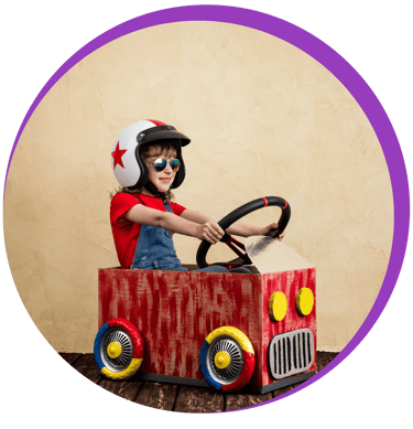 Une petite fille dans une voiture en carton