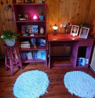 Escritorio con fotos y lampara dentro de una cabaña de madera, lugar de trabajo de Mariel Hilgert