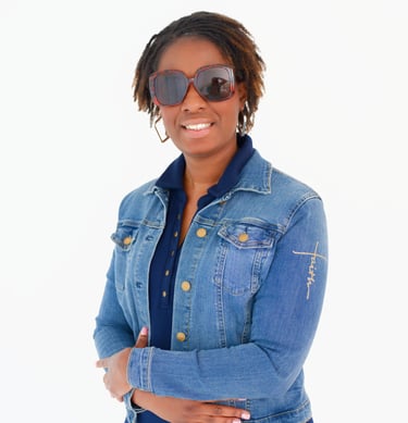 Smiling woman with jean jacket and shades with arms crossed