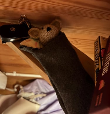 a little crocheted mouse is hanging from a shelf