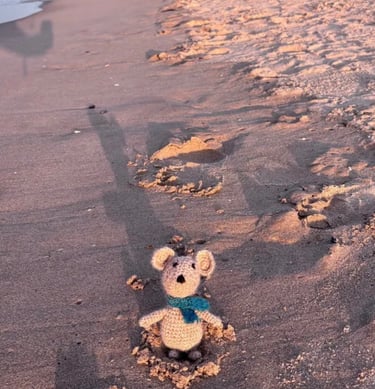 a small crocheted mouse sitting on a beach