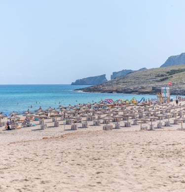 Cala Mesquida beach with sunbeds and people swiming in the sea