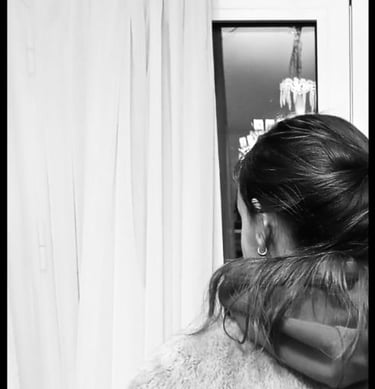 A woman in a coat looking out a window