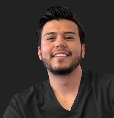 Smiling male healthcare professional in black medical scrubs against a dark background.