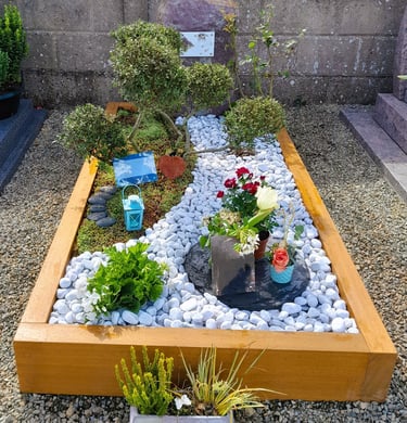Jardin du souvenir avec cadre bois, décor de galets blancs sinueux et artopierre