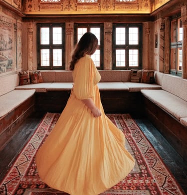 Woman in a yellow dress standing in an ornate Ottoman-style room in Cappadocia