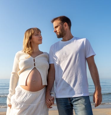 femme enceinte et son marie se tenant la main sur la plage 