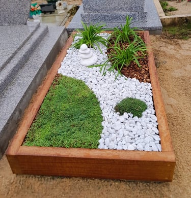 Monument funéraire végétalisé avec cadre en bois, chemin de galets blancs zen, tapis de mousse verte