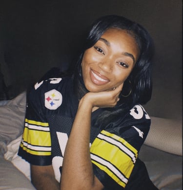 a woman in a jersey shirt is smiling and holding her hand on her chin