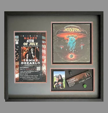 Framed shadow box displaying Boston band memorabilia, including a Tommy DeCarlo concert poster and ticket.