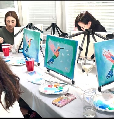paint party women sitting at a table with art work