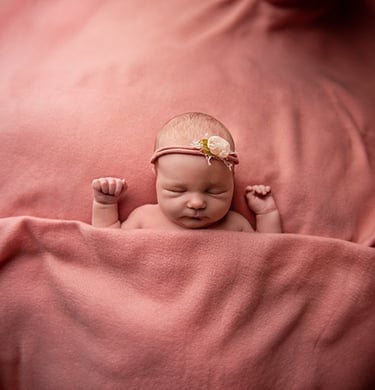 a baby girl is sleeping in a pink blanket
