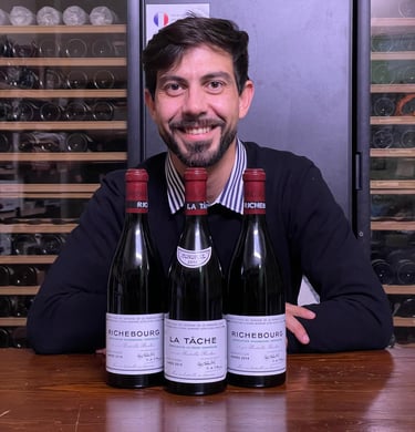 Stefano Cassarino seduto davanti a 3 bottiglie del Domaine de la Romanée Conti