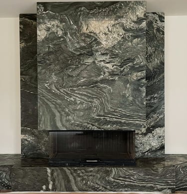 Luxury fireplace feature wall with dramatic dark green and grey bookmatched marble slabs.