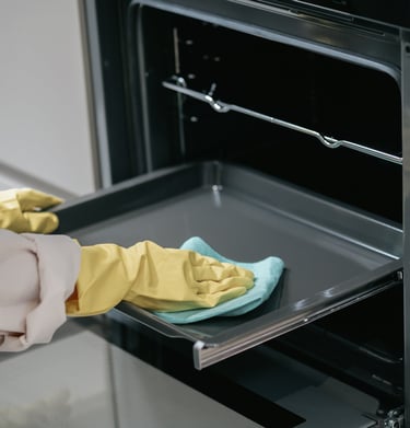 a person cleaning a stove top oven with a yellow glove