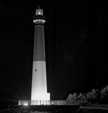 A black-and-white, minimalist photo of the Barnegat Lighthouse at night.