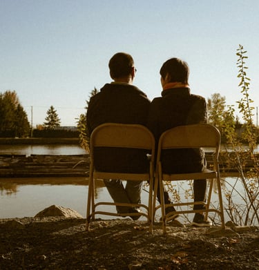 Male couple looking out at a lake concerned about their couples relationship