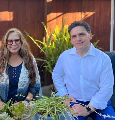 a man and woman sitting on a couch in a backyard