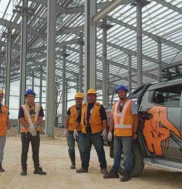 Termite control specialists in safety gear standing by a service truck at a commercial construction site.