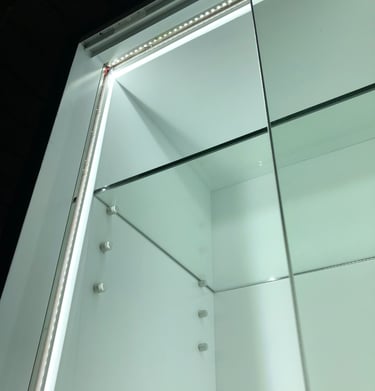 A modern glass display cabinet with integrated LED strip lighting on white shelves.