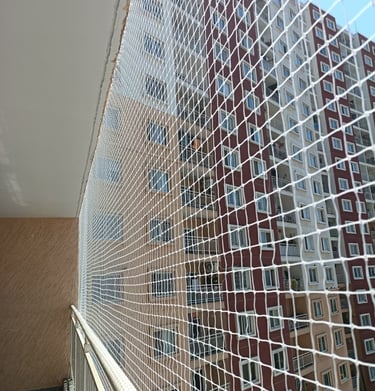 Wide shot showing a colorful safety net enclosing a children's play area on a rooftop.