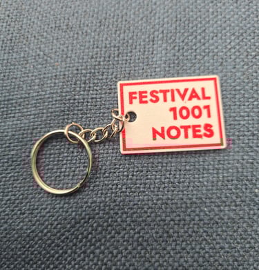 Custom rectangular keychain with red Festival 1001 Notes text on a blue fabric background.