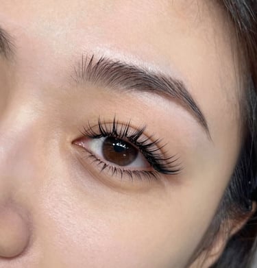 Elegant woman with long, voluminous eyelash extensions smiling softly