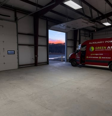 Red Green APU auxiliary power service van parked in a large industrial warehouse garage at sunset.