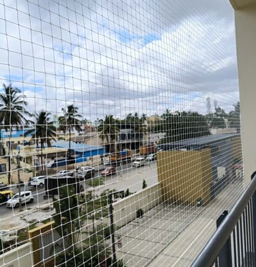 Evening shot of a balcony with safety netting softly illuminated by warm indoor lights.