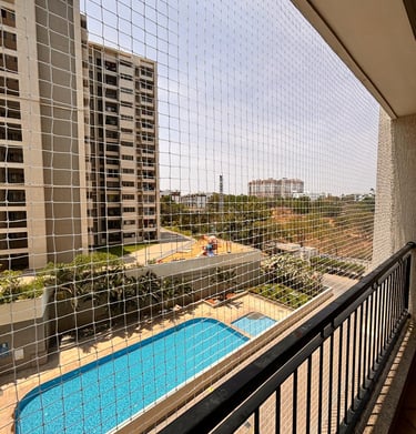 Wide shot showing a full balcony covered with a fine mesh pigeon net, blending with the building fac