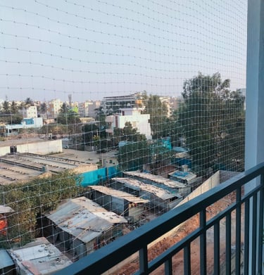 Wide shot showing a balcony fully covered with a durable safety net against a clear sky.