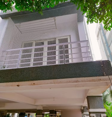 Evening view of a balcony with safety netting softly lit by ambient city lights in Sholinganallur.