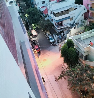 Installation process showing workers fitting anti-pigeon nets on a rooftop edge.