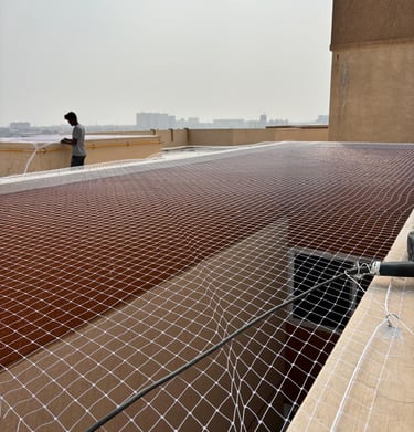 Wide shot of an apartment balcony with a neatly fitted safety net preventing bird entry.