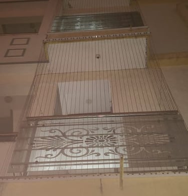 Installation process showing workers fitting anti-pigeon nets on a residential window.