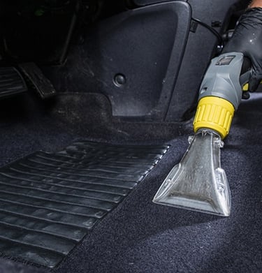a person cleaning a car with a vacuum
