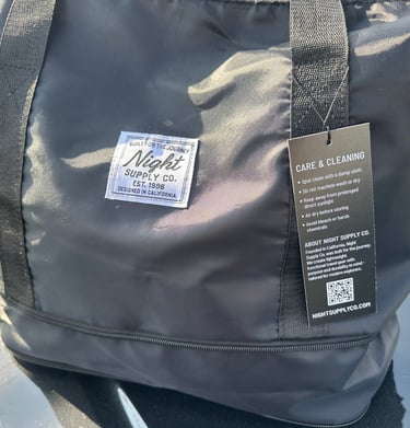 Black Night Supply Co. duffel bag with logo patch and visible care tag details