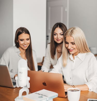 three women sitting at a table with laptops