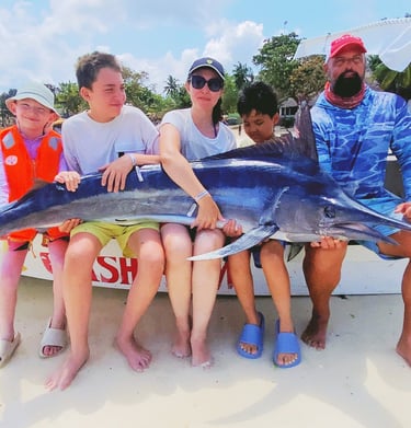 Family celebrating their catch of a black marlin on a Half-Day Fishing Charter in Zanzibar