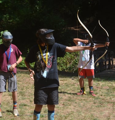 a boy is holding a bow and aiming a bow