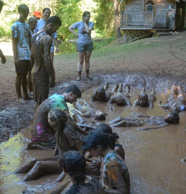 a group of people standing around a muddy puddle