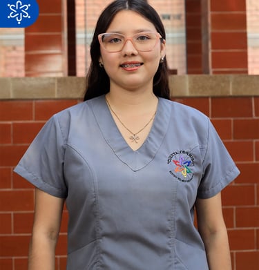 a woman in scrubs and glasses standing in front of a brick wall