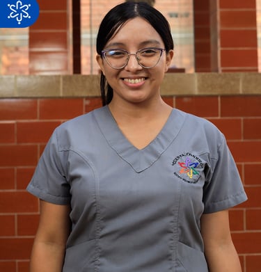 a woman in scrubs and glasses smiling for the camera