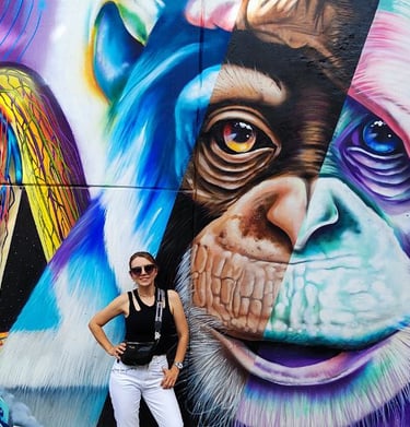 a woman standing in front of a mural of a monkey