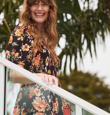 Fashion campaign photography - a woman in a floral dress and a red purse walking down stairs