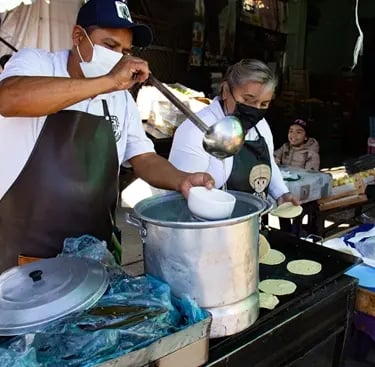 Equipo preparando barbacoa tradicional y sirviendo consomé en puesto en Querétaro.