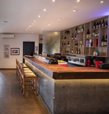 Balcão sushi bar do Kaizen e iluminação suave em ambiente contemporâneo
